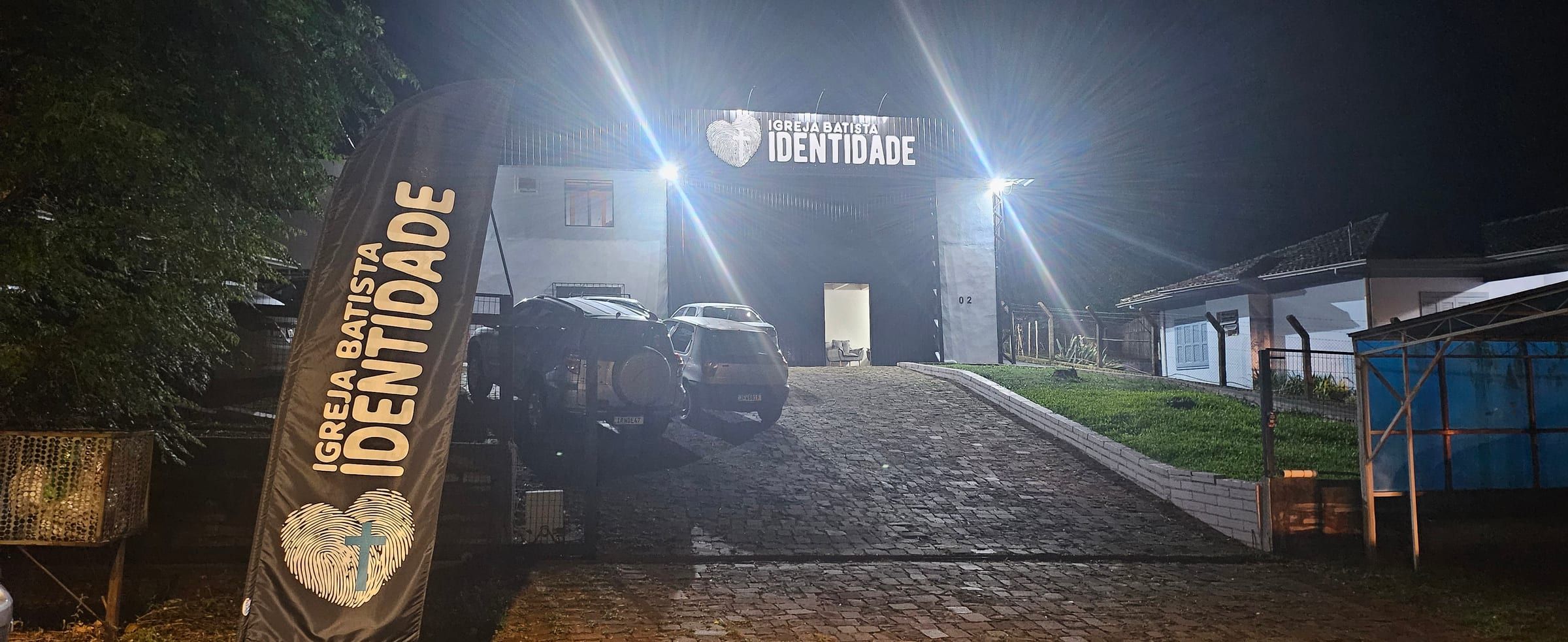 Fachada da Igreja Batista Identidade à noite, com o letreiro iluminado.